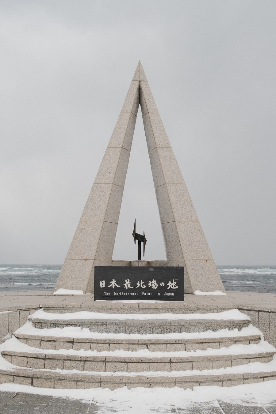 雪中的日本最北端纪念碑，身后是灰色的海