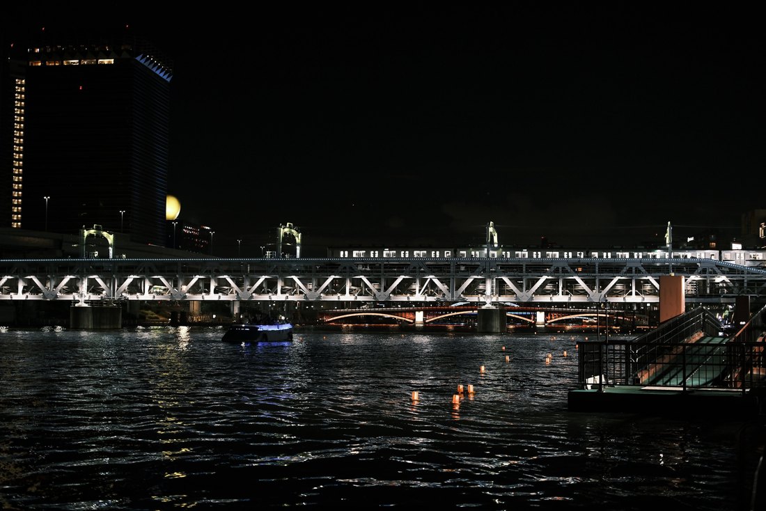 隅田川的夜晚：桥上的列车、河面的小船和一盏盏漂浮的灯